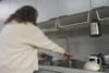 Valerie Vetter at her sink, pouring water into a mug.