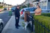 A man stands at the gate to a driveway to chat to a neighbour while a dog yaps and plays around.