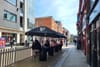 Groups sit at outdoor tables under umbrellas with the Guinness logo on them.