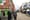 Two men stand on the corner of a city centre street. One is pointing up at something opposite.