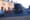 Two men in high-viz trail a waste collection truck as it trundles down a street past a two-storey redbrick terrace in Inchico
